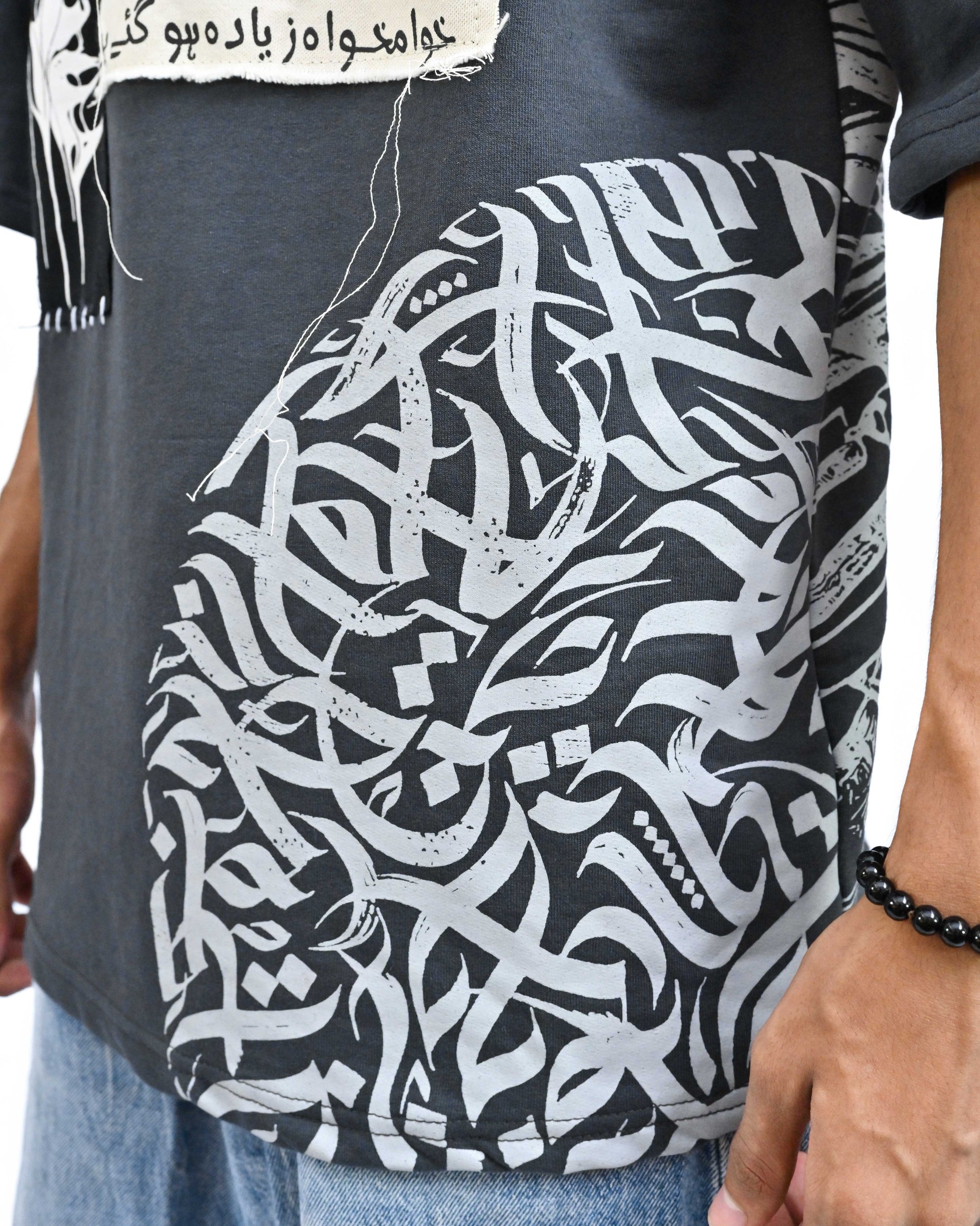 Person wearing "Chronicle" a white And Black graphic t-shirt with text on the back, standing against a white background made in pakistan