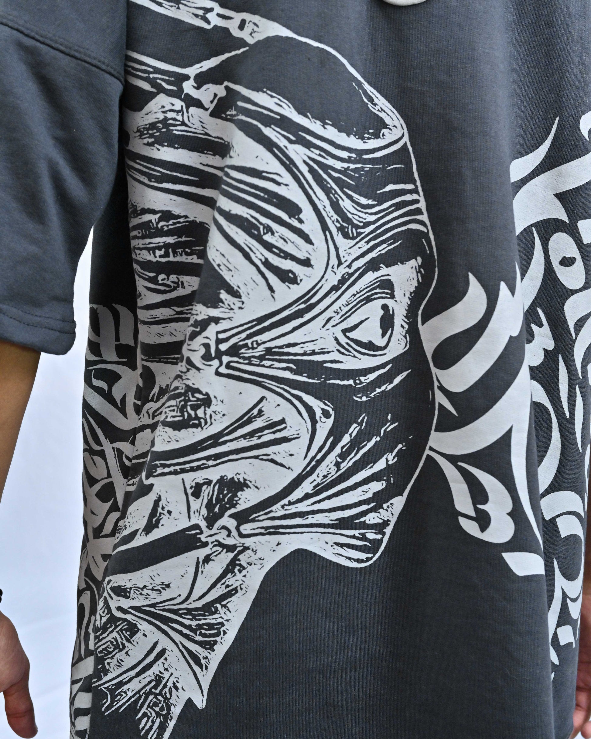 Person wearing "Chronicle" a white And Black graphic t-shirt with text on the back, standing against a white background made in pakistan