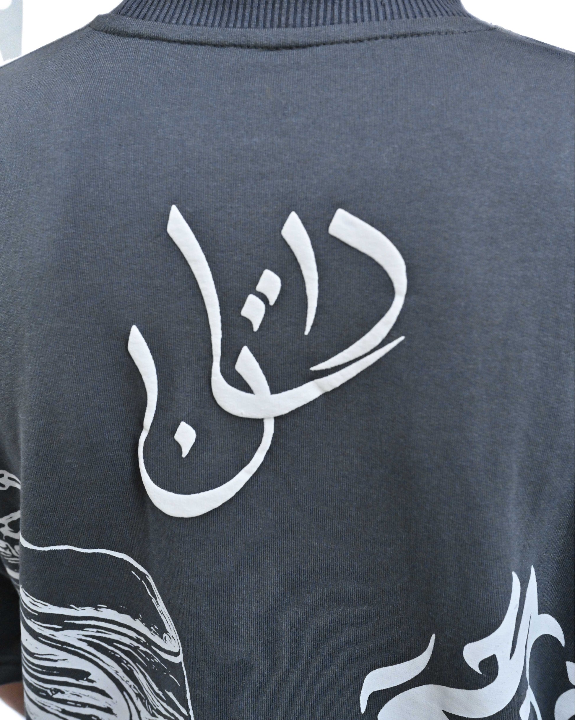 Person wearing "Chronicle" a white And Black graphic t-shirt with text on the back, standing against a white background made in pakistan