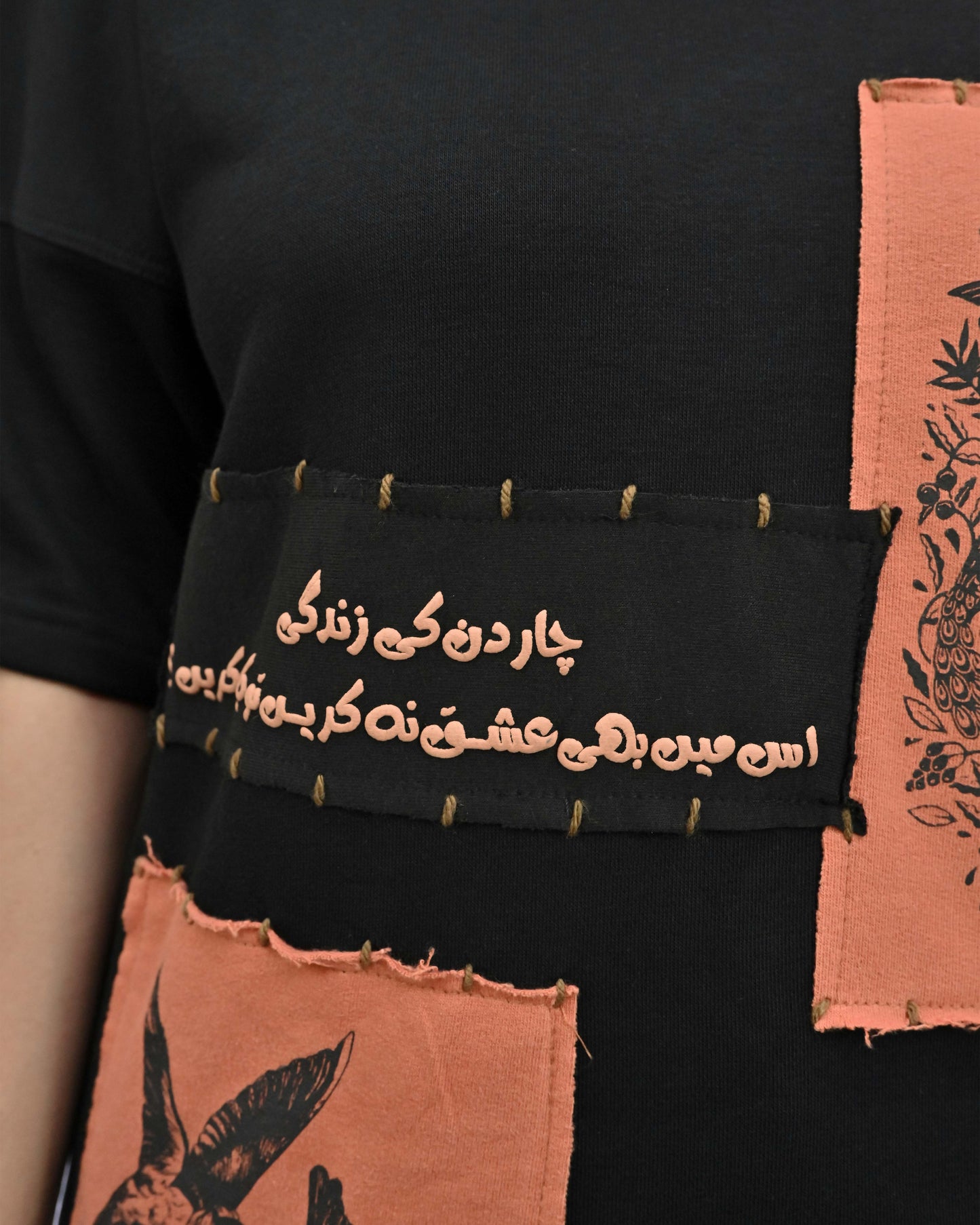 Person wearing "Vese in Stone" a Cream And Black graphic t-shirt with text on the back, standing against a white background made in pakistan