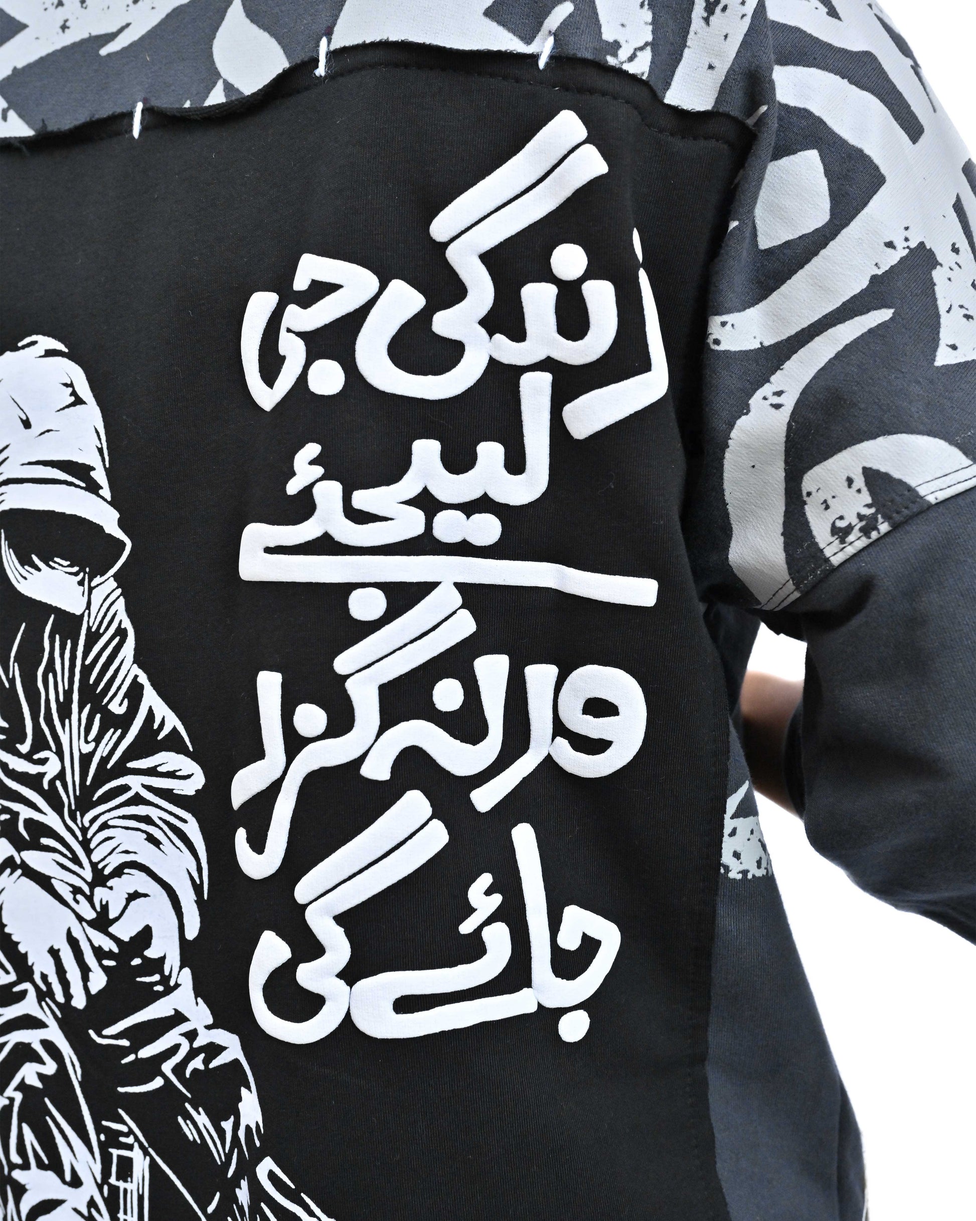 Two people wearing matching black t-shirts with white designs, standing back-to-back on a white background.