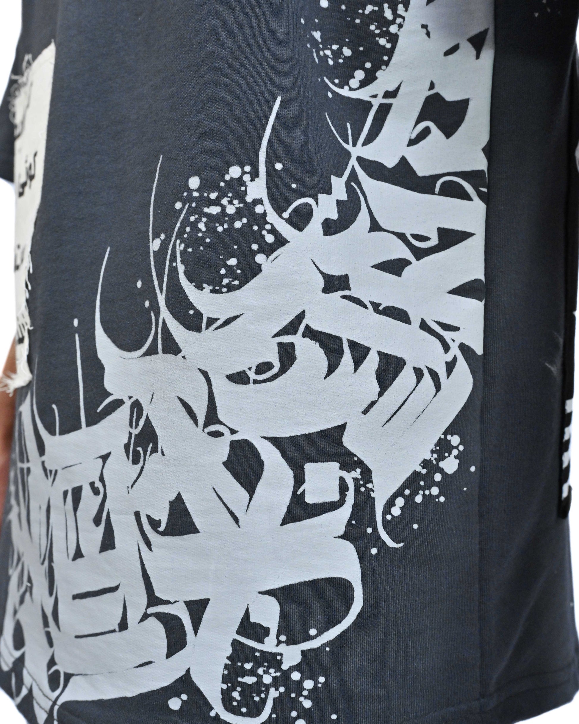 Person wearing "Stone & Spirit" a black and white graphic t-shirt with text on the back, standing against a white background.